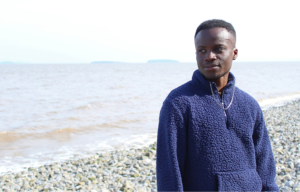 Adjei standing on a rocky beach