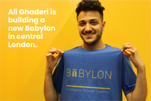 Ali Ghaderi holding up his shirt Text on shirt - Babylon. Migrants Project. Community Through Creativity.
