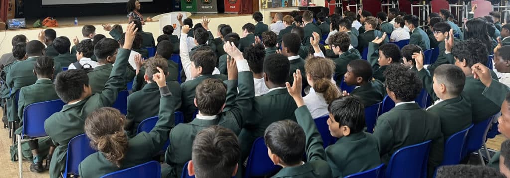 A group of people in a classroom raising their hands