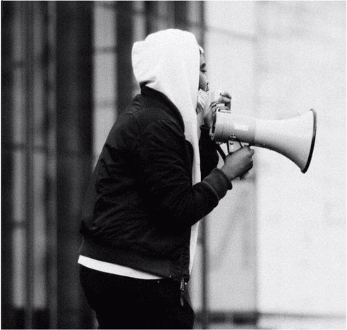 A person with a hoodie speaking into a megaphone