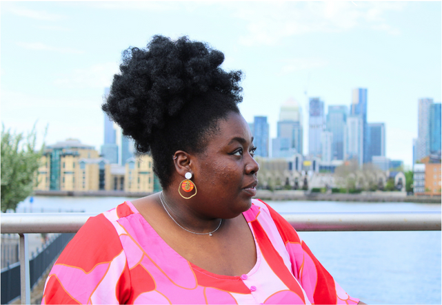 Shania-Sophia Dunbar Ives in front of a city skyline looking into the distance.