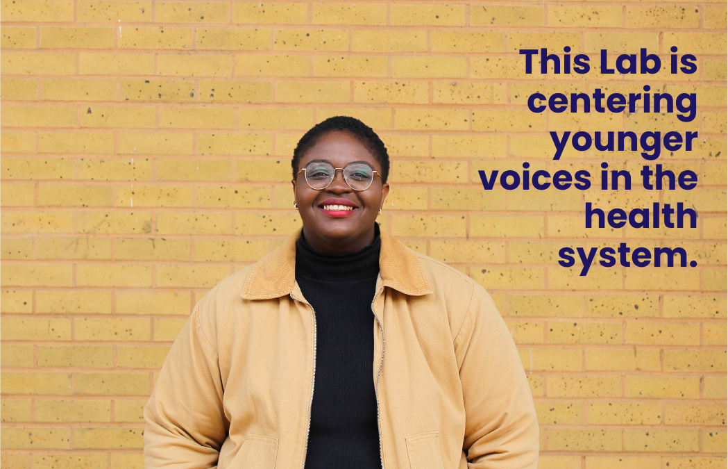 Fola Afolabi smiling in front of a beige brick wall. Text in picture: This Lab is centring younger voices in the health system.
