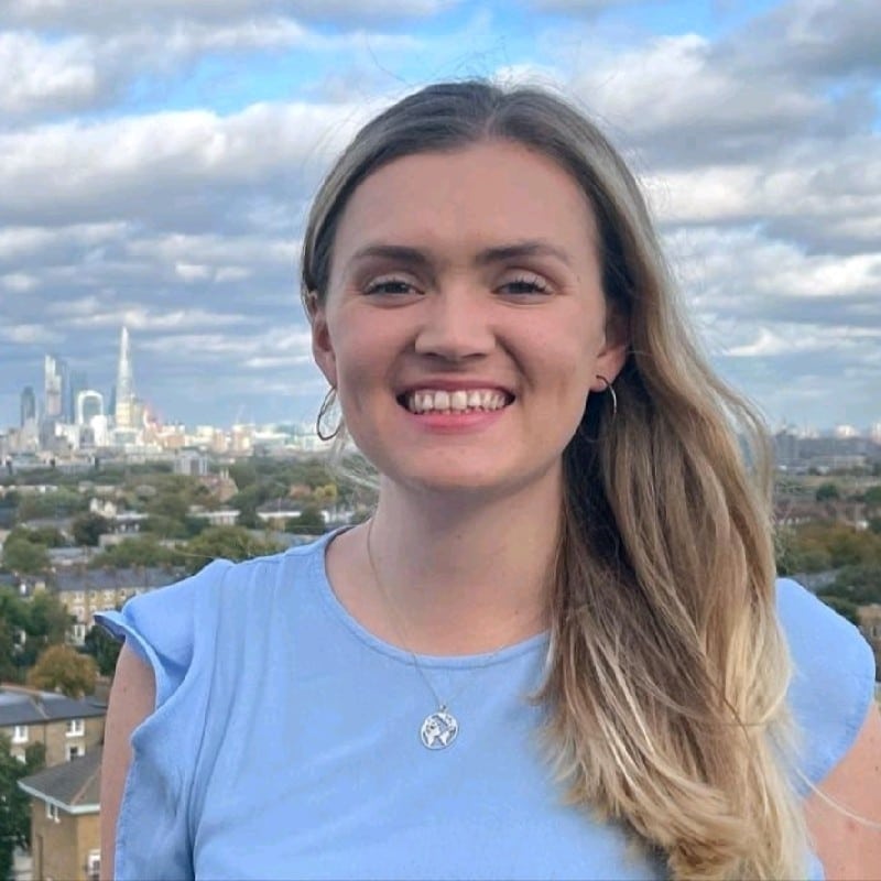 A women in a blue top smiling at a camera