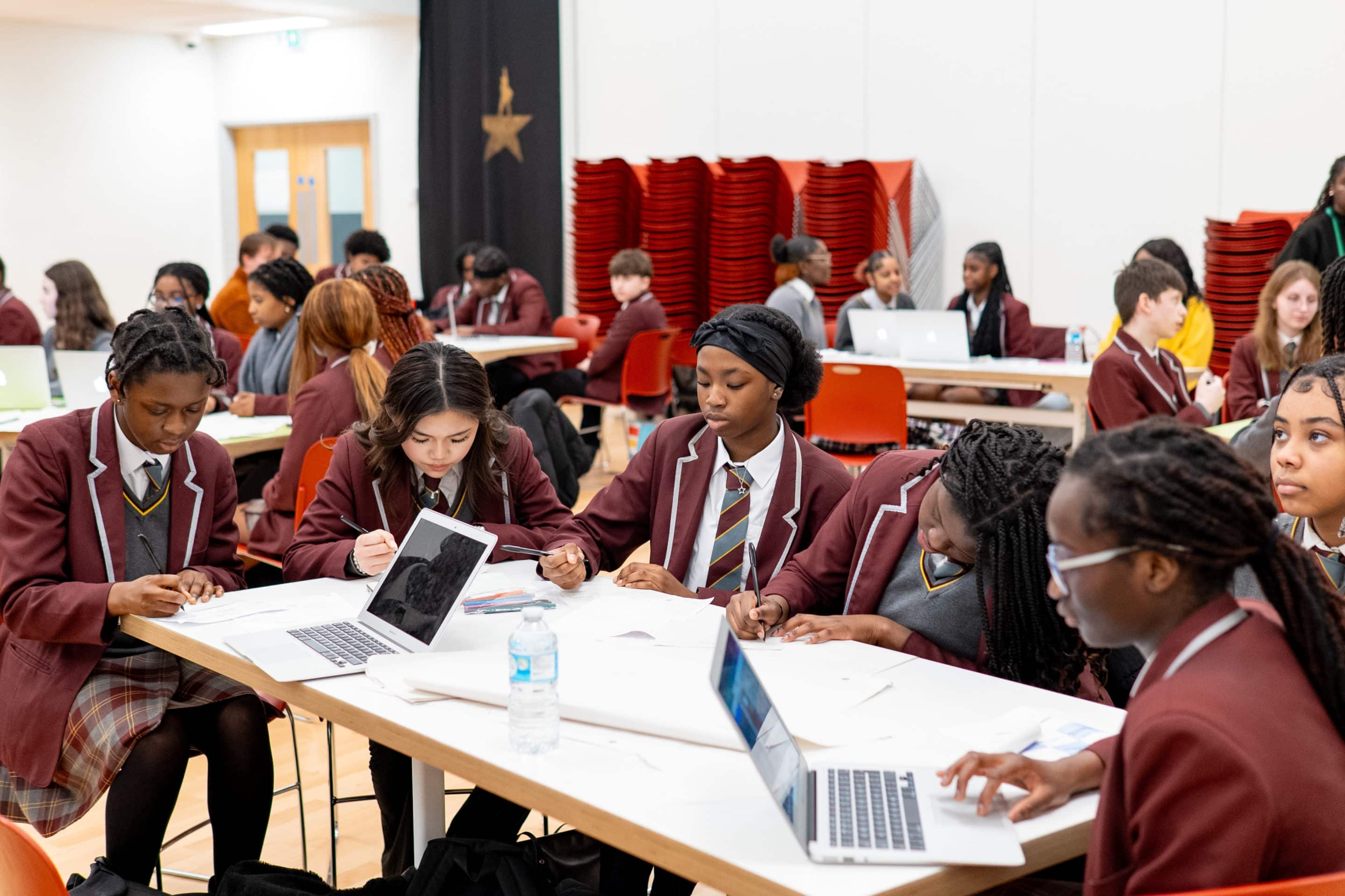 A picture of students sitting at a table in a school hall