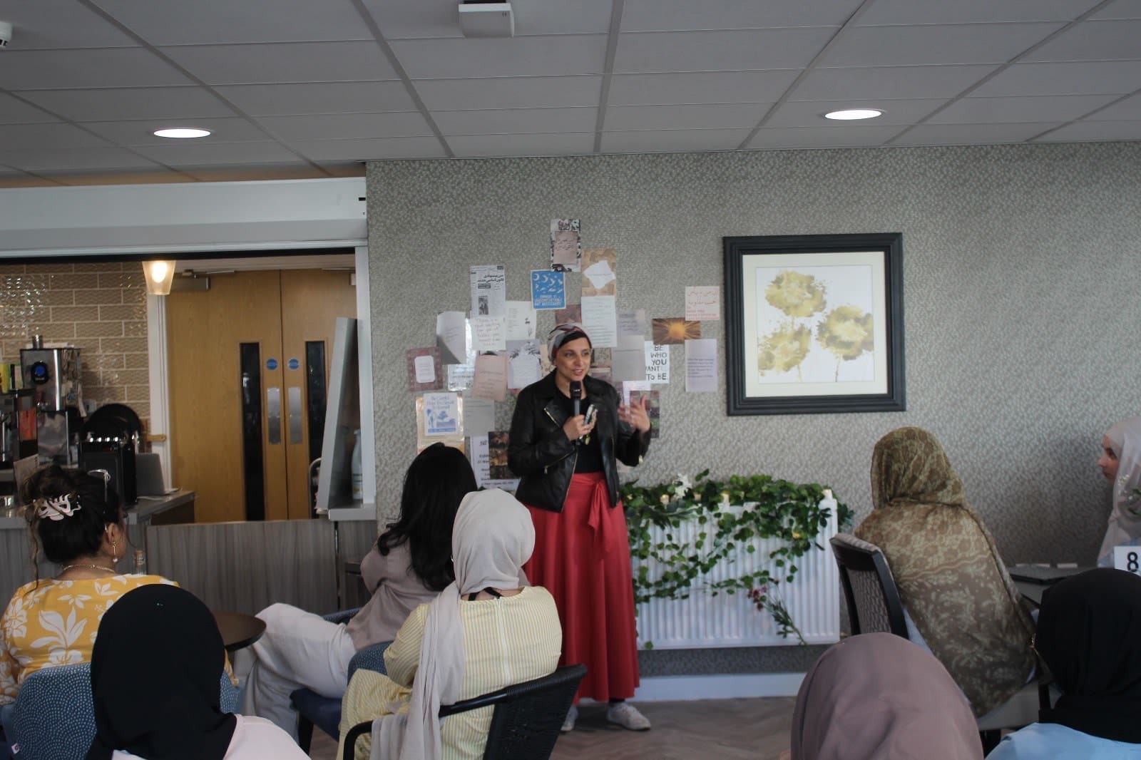 A women with a mic speaking to a room of people
