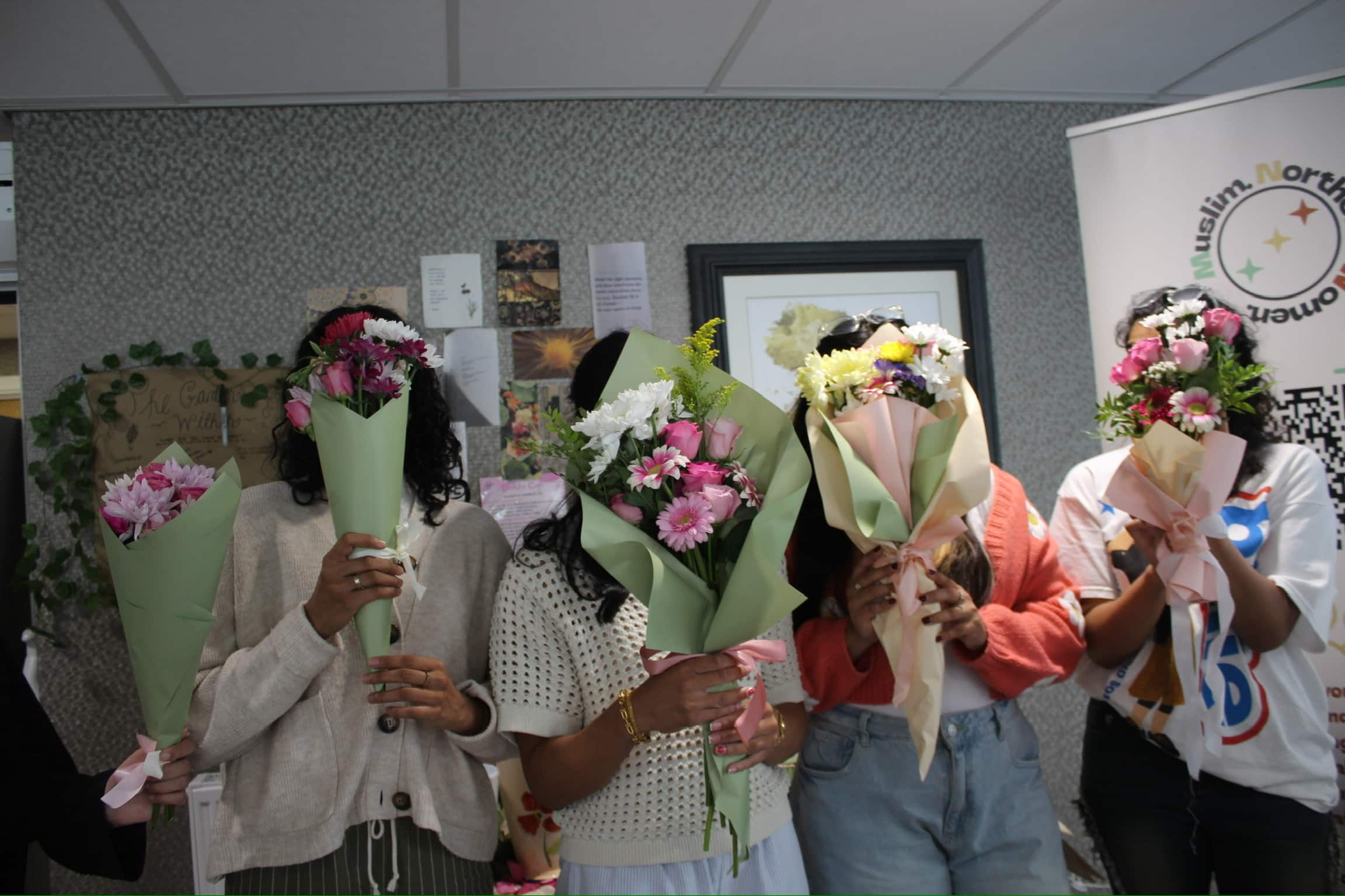 4 girls holding flowers covering their faces