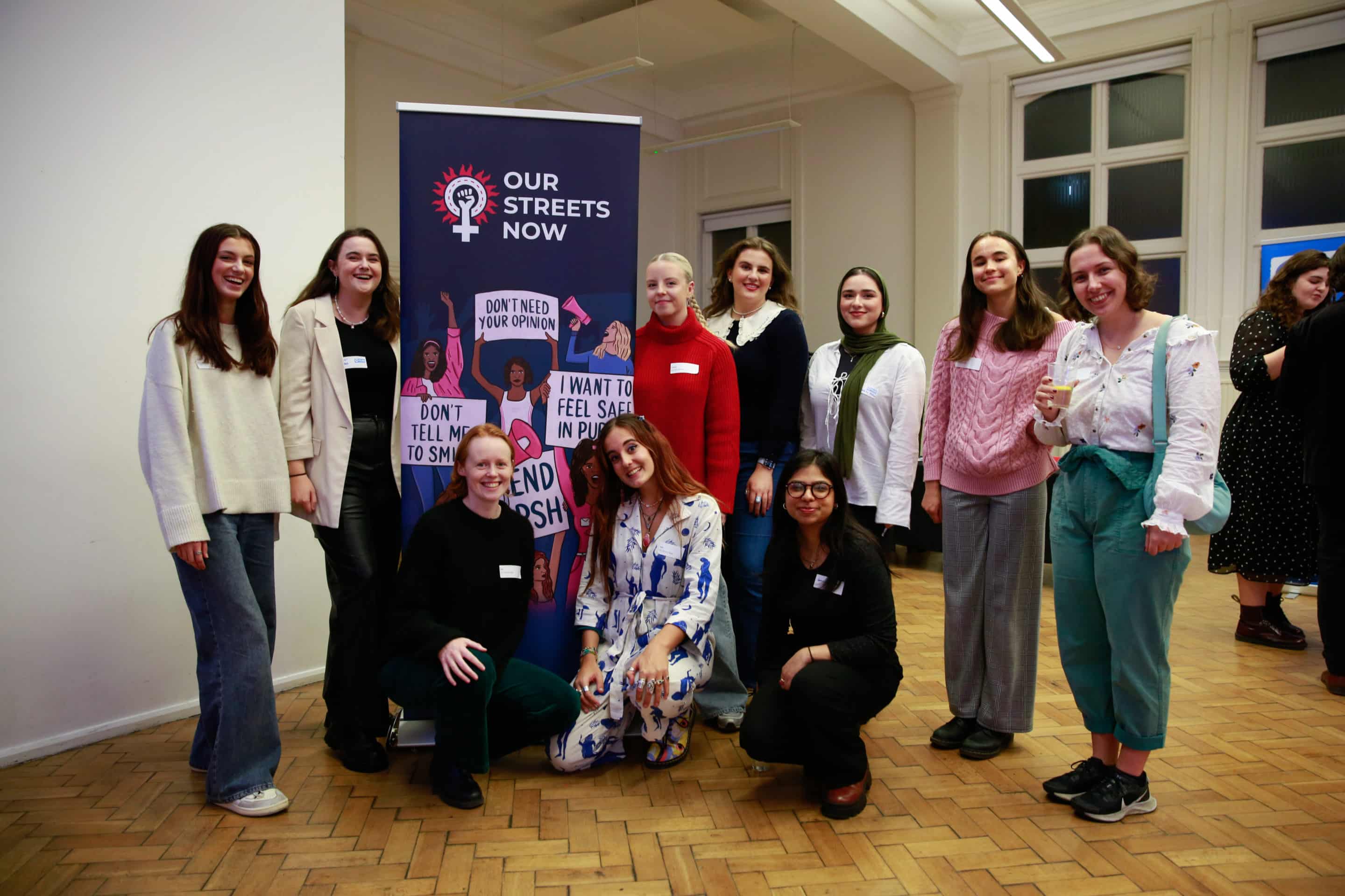 10 people taking a group picture beside a banner