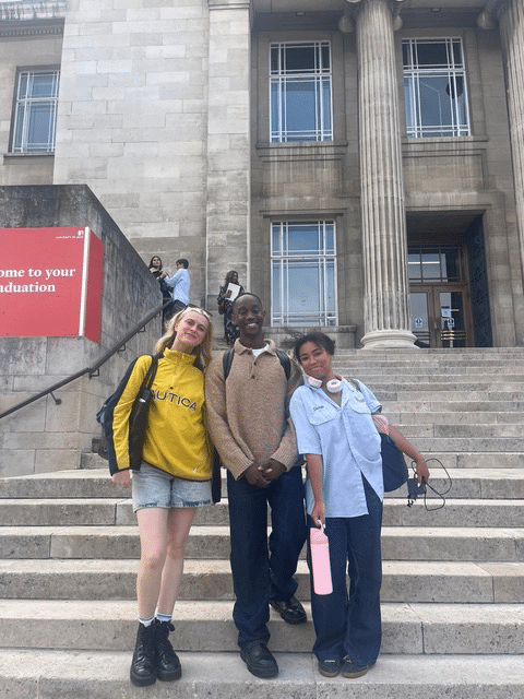 3 people taking a picture togther in front of a building